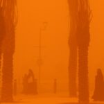 Women walk amidst a severe dust storm in Kuwait City on May 23, 2022.