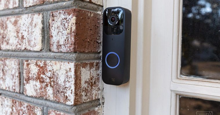 The black Blink Video Doorbell hung up on a brick wall outside of a house.