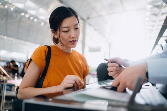 Young Asian woman travelling by airplane and doing check-in at airline check-in counter at airport terminal