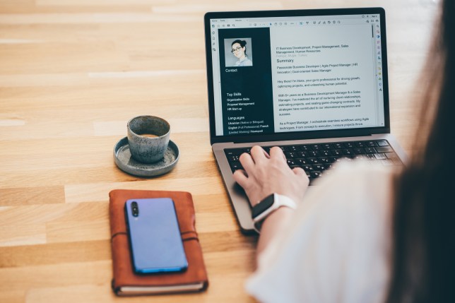 Young business woman searching for job online. Woman writing resume on laptop.