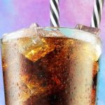 A glass of Coca-Cola on a colourful pink, purple, and blue fluffy background