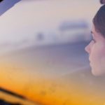 Young woman sitting in car behind glass window