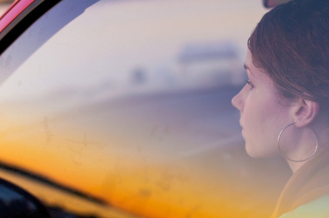 Young woman sitting in car behind glass window