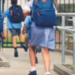 School children wearing uniforms and carrying backpacks, running away