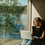 Woman using laptop near window