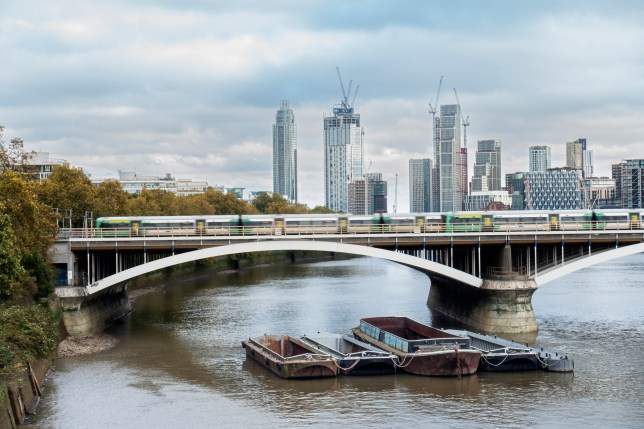 Office buildings a train passing over a bridge and a river with empty barge boats