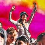 A woman on someone's shoulders in a crowd at a festival