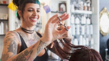 Woman with tattoos cutting woman's hair