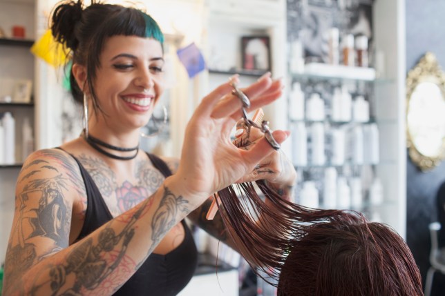 Woman with tattoos cutting woman's hair