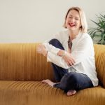 Jane Galloway sitting on a sofa and smiling/laughing