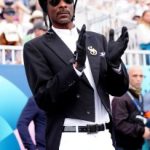 Snoop Dogg watching the Dressage Team Grand Prix Special at the Chateau de Versailles at the 2024 Paris Olympic Games on Aug. 3, Roeckl gloves, givenchy star aviator sunglasses, Shadowmatt helmet, equestrian inspired dressed outfit look