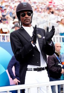 Snoop Dogg watching the Dressage Team Grand Prix Special at the Chateau de Versailles at the 2024 Paris Olympic Games on Aug. 3, Roeckl gloves, givenchy star aviator sunglasses, Shadowmatt helmet, equestrian inspired dressed outfit look