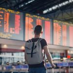 Man walking with backpack and suitcase walking through airport terminal