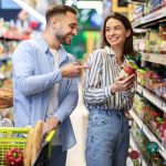 Young happy couple with the cart shopping in supermarket