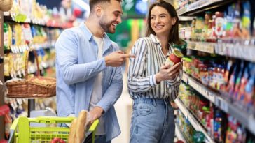 Young happy couple with the cart shopping in supermarket