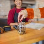 Unrecognizable female customer leaving the tips at the tip jar