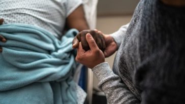 Son holding father's hand at the hospital