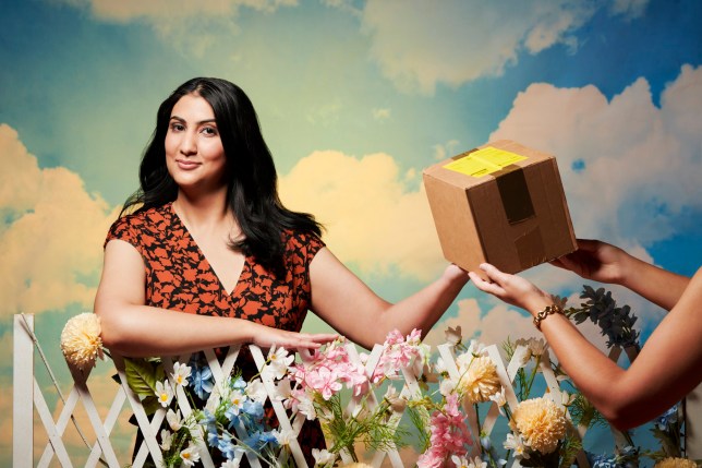 Vrinda Guha, who started taking Wegovy through a private company, takes a cardboard parcel over a floral fence. She wears a black and red floral dress