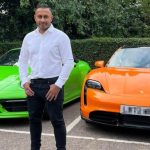 Mindy standing in front of his two Porsche's - green and orange