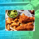 A plate of fish, chips and mushy peas is pictured against a backdrop of M&S supermarket shelves