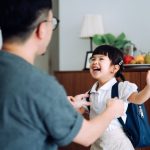 Excited and happy school girl getting dressed with her father in the living room and preparing for her first day at school