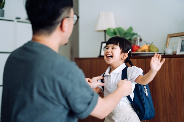 Excited and happy school girl getting dressed with her father in the living room and preparing for her first day at school