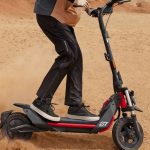 The Segway-Ninebot ZT3 Pro all-terrain electric scooter kicking up sand while being ridden in a desert setting.