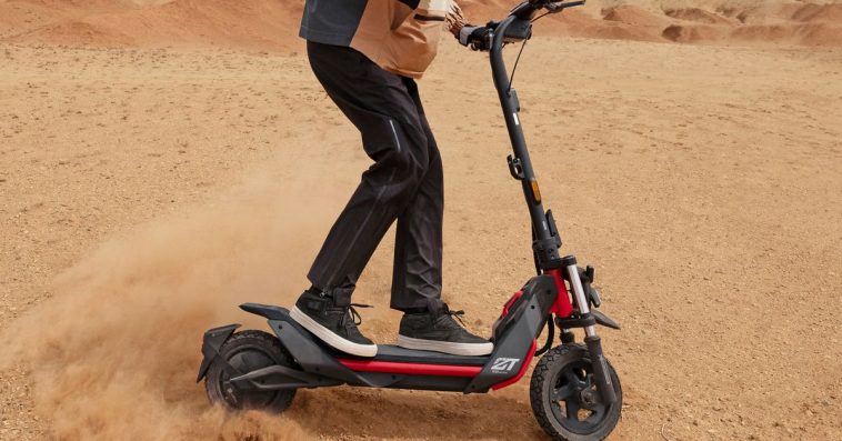 The Segway-Ninebot ZT3 Pro all-terrain electric scooter kicking up sand while being ridden in a desert setting.