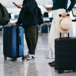 Cropped shot of group of airline passengers with suitcases standing in queue, waiting at check-in counter at International airport. Ready for a trip. Business travel. Travel and vacation concept