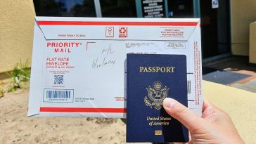 A photo of a person holding a US passport and an envelope.