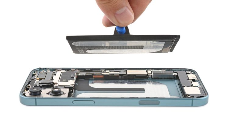 A picture of a partially deconstructed iPhone 16, with one side removed and the battery being lifted from it.