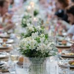 Group of people having dinner at wedding reception table at back yard.