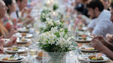 Group of people having dinner at wedding reception table at back yard.