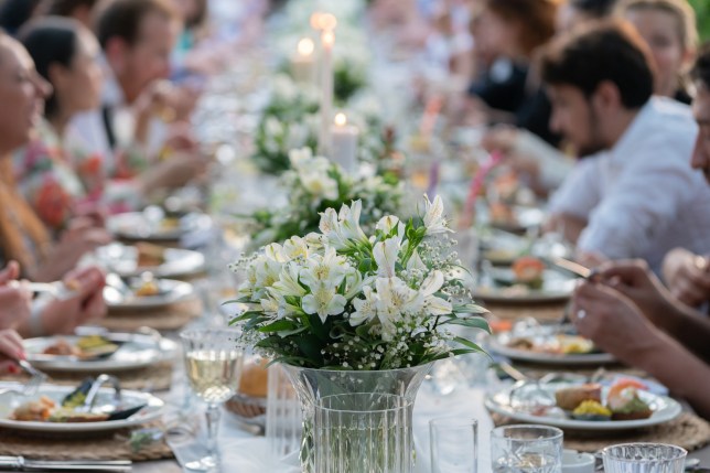 Group of people having dinner at wedding reception table at back yard.