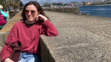 Sionna Hurley-O'Kelly pictured sitting by a concrete wall, resting her face on her hand.