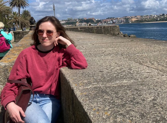 Sionna Hurley-O'Kelly pictured sitting by a concrete wall, resting her face on her hand.