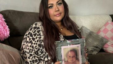 Chloe McCreery sitting on a sofa holding up a photo of Logan in a frame