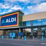 The frontage and brand logo of a branch of German discount retailer Aldi, taken in a local retail park on Wirral, UK on a sunny afternoon