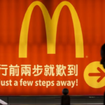 A silhouette of a person in China walking past an illuminated McDonald’s sign.