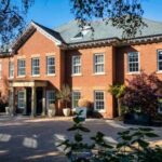 The exterior of Jurgen Klopp's former home just north of Liverpool in Merseyside. It is a large red brick home with a grey roof and columns around the door