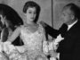 Christian Dior (1905 - 1957) French couturier, with a mannequin in one of his own designs, a satin evening gown called Blenheim.