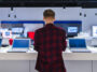 Customer browsing laptops in a store, reflecting 2024 PC shipment growth driven by hardware refresh cycles and Windows 10 end-of-support.