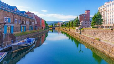 A scenic view of Otaru canal in Otaru, Japan, with houses on either side and a boat sat on the water.