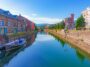 A scenic view of Otaru canal in Otaru, Japan, with houses on either side and a boat sat on the water.